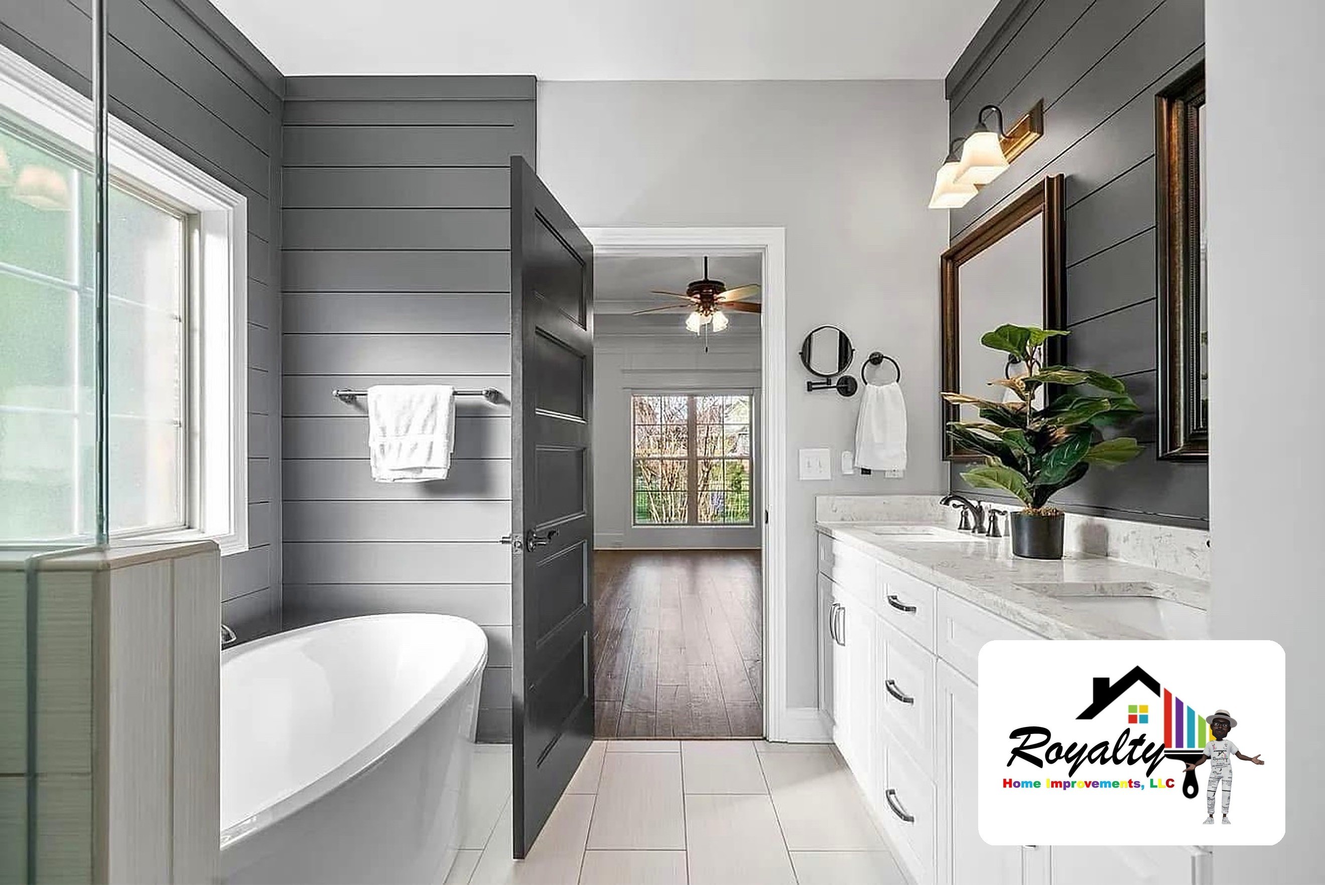 Remodeled gray bathroom with a white freestanding tub, vanity and paneled walls