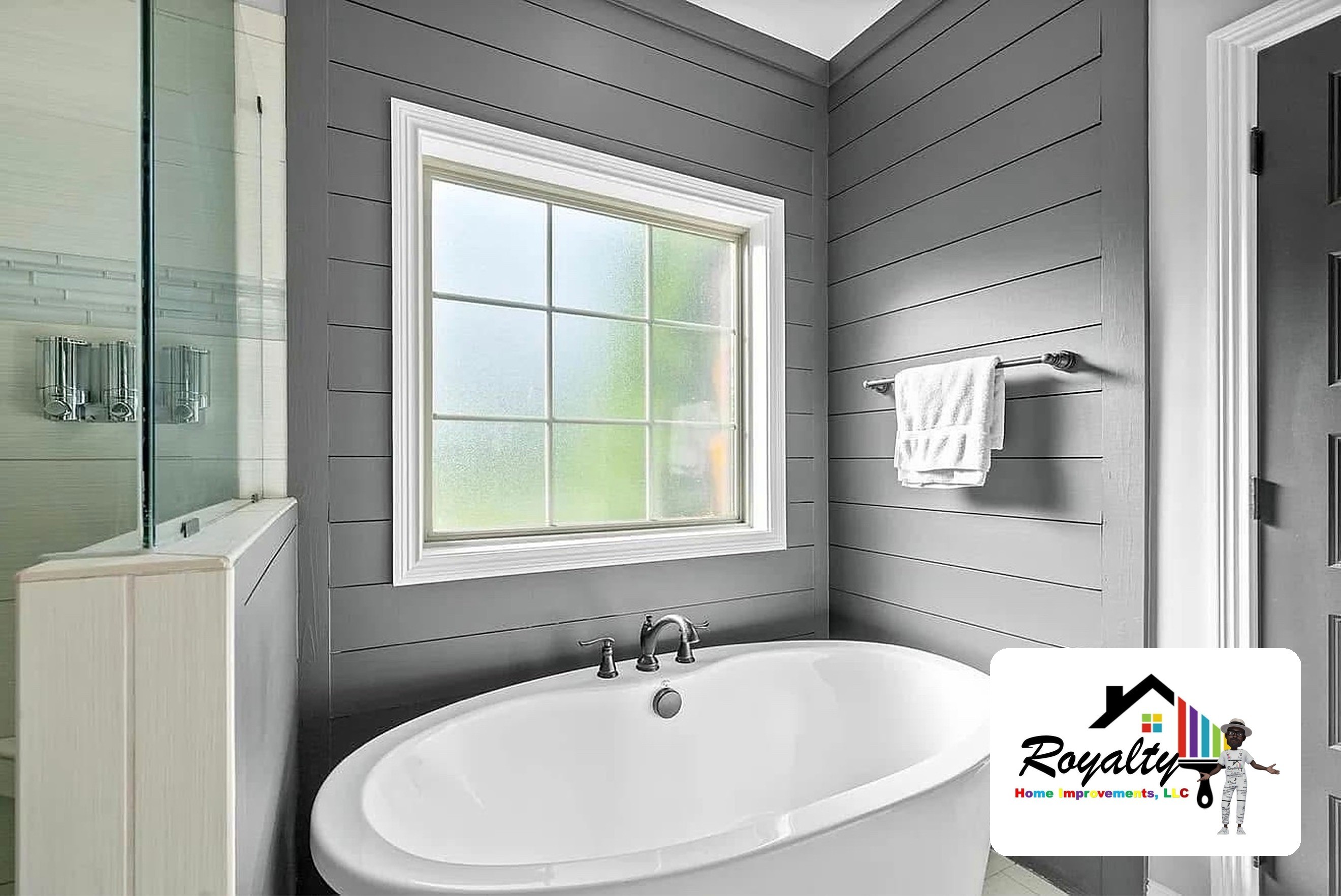 Bright gray bathroom with a white freestanding tub beneath a window