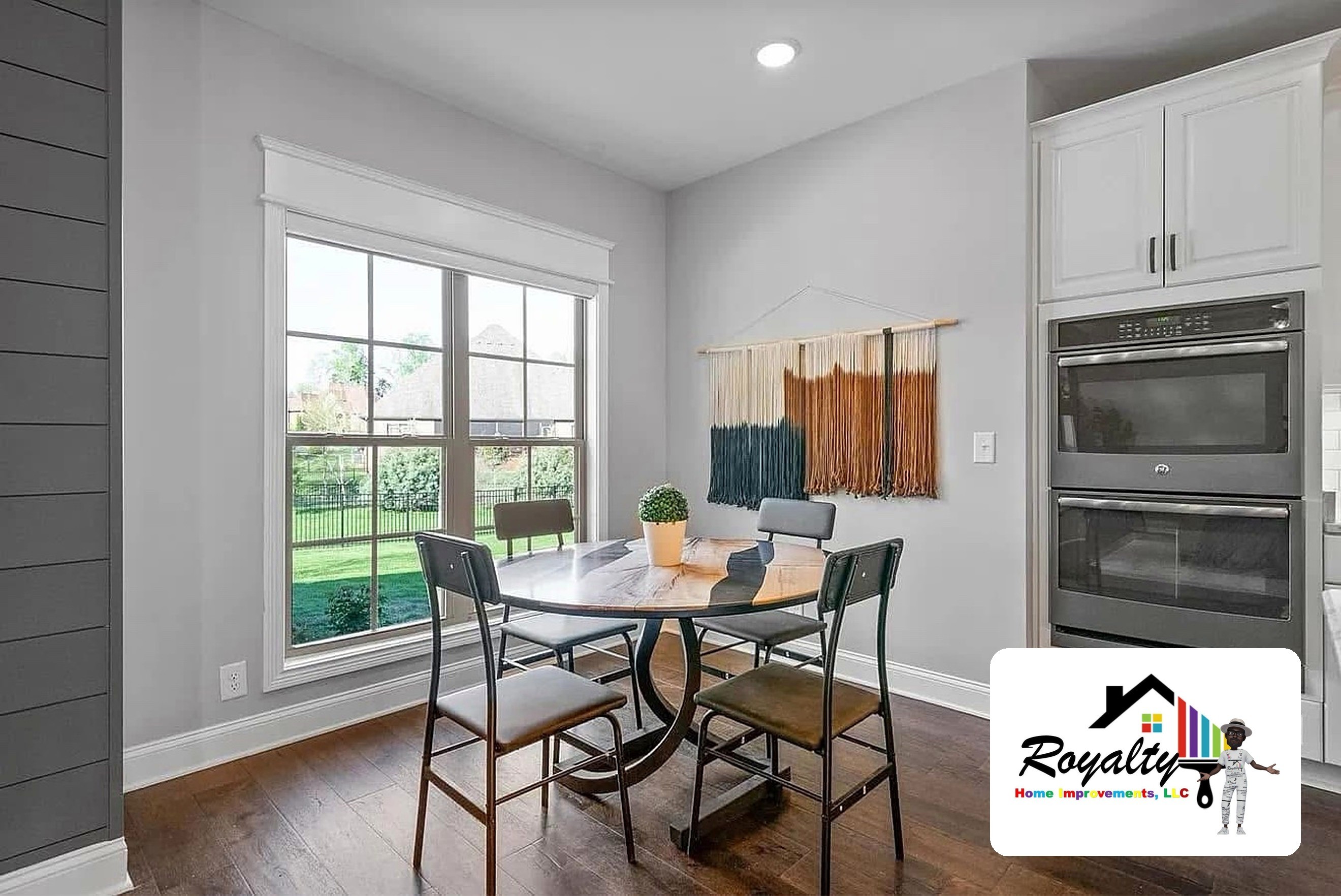 Sunlit dining space and white kitchen with black countertops