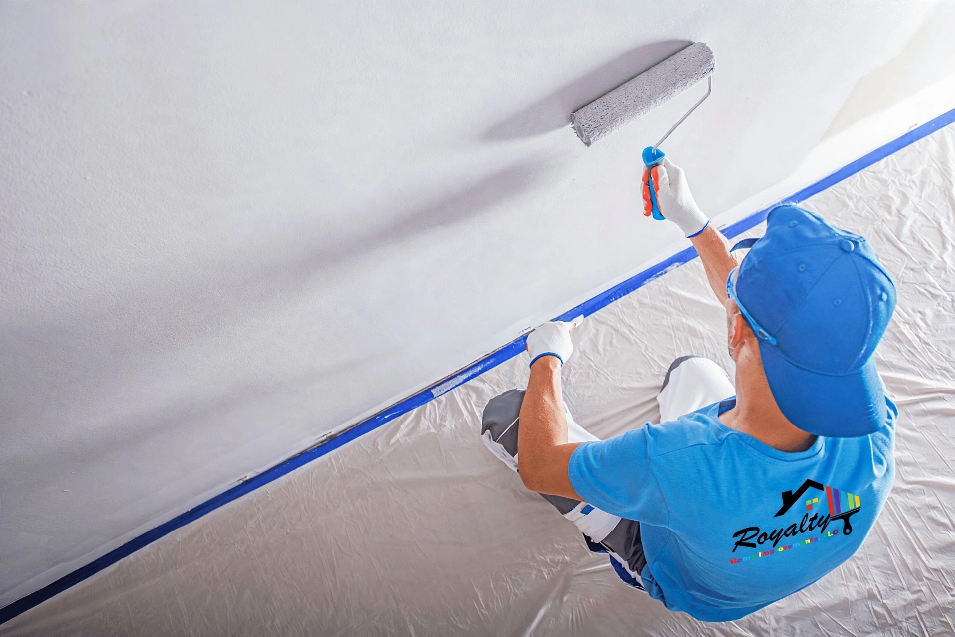 Professional painter in a Royalty Home Improvement shirt rolling an interior ceiling